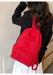 Vue détaillée du sac à dos rouge vif avec multiples poches pour les déplacements quotidiens.