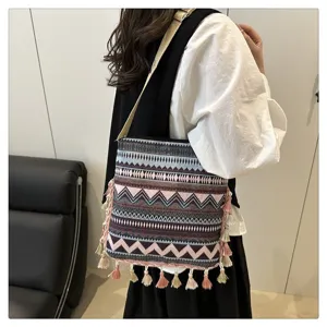 Sac bandoulière tissé style ethnique détail montrant motifs géométriques et glands ludiques.