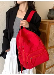 Vue détail de sac à dos décontracté rouge, sac en nylon avec plusieurs poches zippées.