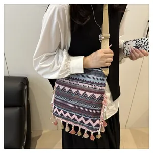 Sac à bandoulière ethnique bohème en toile avec des pampilles colorées et des motifs géométriques.