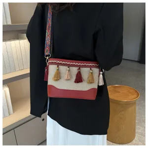 Sac bandoulière en toile bohème détail, décoration de glands ethniques et sangle colorée.