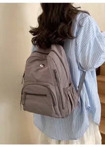Vue détaillée du sac à dos décontracté à plusieurs poches porté par le modèle, solides.