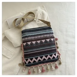 Sac bandoulière tissé de style ethnique pour femmes avec motif géométrique et pompons.
