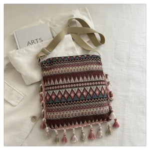 Vue détaillée du sac bandoulière ethnique rétro tissé avec des pompons colorés et des motifs.