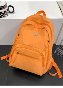 Gros plan du sac à dos décontracté orange vif montrant la poche zippée avant et la texture.