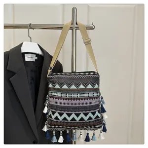 Vue détaillée du sac bandoulière tissé ethnique avec motifs géométriques et pompons.