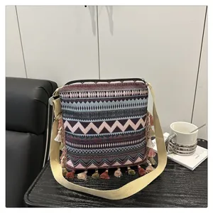 Vue détaillée du sac bandoulière de style ethnique avec motifs géométriques et pompons.
