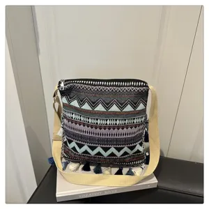 Vue détaillée du sac bandoulière tissé de style ethnique avec motifs géométriques et glands.