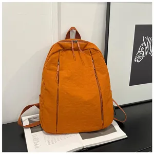 Détail d'un sac à dos minimaliste orange, présentant une poche zippée et un tissu en nylon.