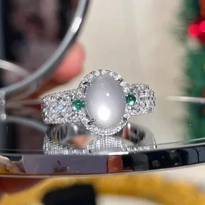 Vintage oval white moonstone ring with green side stones and sparkling pavé band detail.