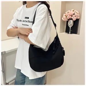 Vue détaillée d'un sac porté épaule en nylon noir, présentant une forme souple et style casual.