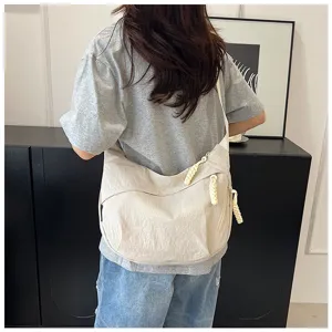 Sac bandoulière décontracté en nylon forme croissant, avec fermetures éclair nouées et style.