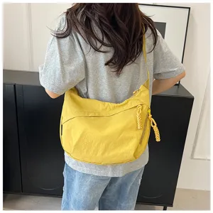 Vue détaillée du sac jaune en nylon montrant la fermeture éclair et les tirettes texturées.