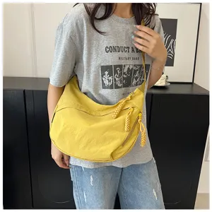 Vue détaillée du sac bandoulière jaune en nylon avec tirettes de fermeture tressées.
