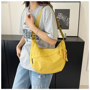 Vue détaillée du sac hobo bandoulière en nylon jaune avec pompon tressé et sangle.