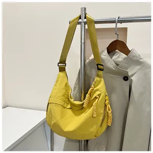 Vue détaillée du sac bandoulière dumpling en nylon jaune décontracté avec tirettes tressées.