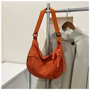 Vue detaillee du sac porte-epaule hobo en nylon orange avec texture et noeud decoratif.