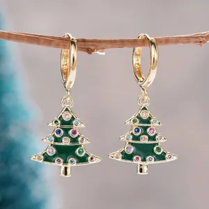 Detalle de pendientes árbol de navidad dorados, circonitas de colores, joyería festiva.
