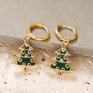 Primer plano de pendientes dorados de árbol de navidad con pedrería y esmalte verde.