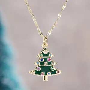 Primer plano de un collar con colgante de árbol de navidad dorado con pedrería de colores.