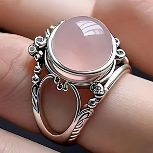 Primer plano detallado de anillo vintage con piedra rosa, diseño ornamental y estilo elegante.
