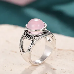 Primer plano detallado del anillo vintage con piedra de resina rosa y banda plateada esculpida.
