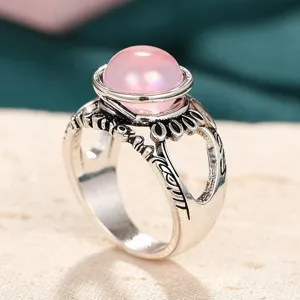 Anillo vintage de color plateado con elegante piedra de resina rosa y banda tallada.