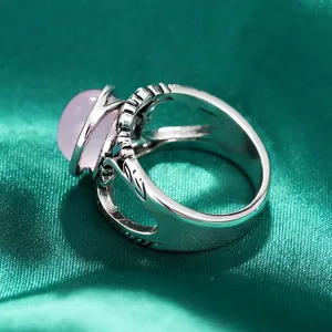 Detalle de anillo de plata retro exótico, piedra de resina rosa con banda tallada.