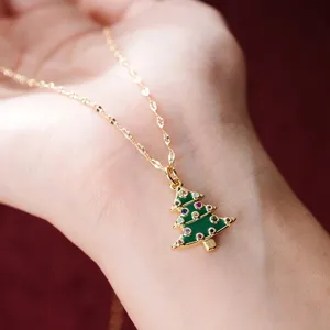Vista detallada del collar con colgante de árbol de navidad dorado y piedras de colores, diseño.