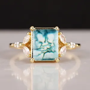 Primer plano detallado de un anillo chapado en oro estilo vintage con piedra azul y circonitas.