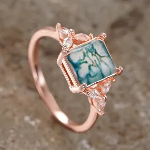 Anillo de piedra verde cuadrada con banda de oro rosa y detalles de circonita cúbica vista detallada