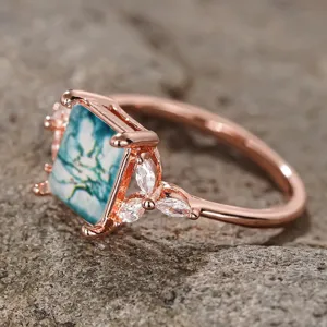 Primer plano de anillo vintage en oro rosa con piedra cuadrada y zirconias brillantes.