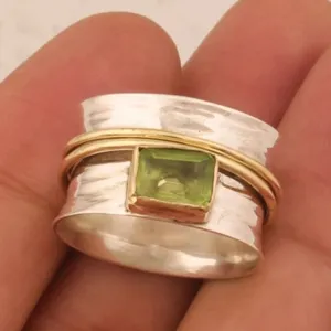 Elegante anillo spinner ancho con banda de plata martillada, detalles dorados y piedra.