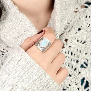 Close-up detail of vintage wide silver carved ring featuring glowing oval moonstone design