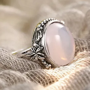 Close-up detail of retro vintage style silver flower ring with pink cabochon gemstone texture.