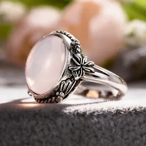 Macro detail shot of a vintage silver ring featuring an oval pink stone and carved floral band.