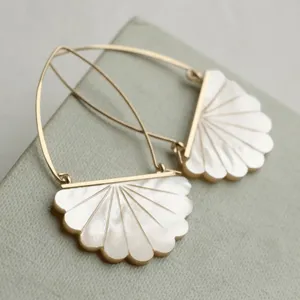 Primo piano di eleganti orecchini a ventaglio con delicate monachelle dorate e design raffinato.