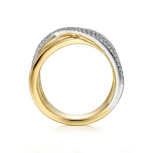 Vista detallada de un anillo cruzado bicolor con bandas de oro y plata y piedras brillantes.