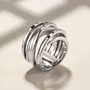 Vista detallada de un elegante anillo cruzado de metal plateado, estilo hip-hop moderno.