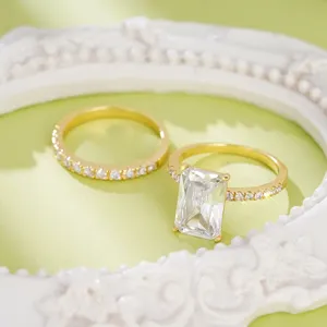 Exquisito juego de anillos de circonita talla esmeralda, detalle de pavé dorado en primer plano.