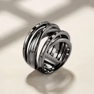 Detalle en primer plano del anillo entrelazado de metal oscuro con un diseño geométrico refinado.