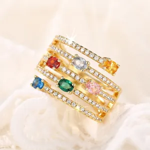 Detalle de primer plano de anillo con piedras coloridas, banda de oro y circonitas.