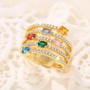 Exquisito anillo dorado multicapa con gemas ovaladas de colores y circonitas brillantes.
