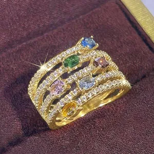 Primer plano detallado de un anillo dorado multicapa con piedras preciosas de colores.