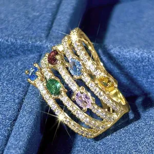 Exquisito anillo dorado multicapa con gemas de colores brillantes y detalles de cristales.