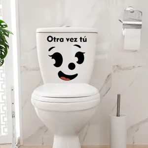 Close-up detail of funny smiley face toilet sticker with Spanish text for bathroom decor.