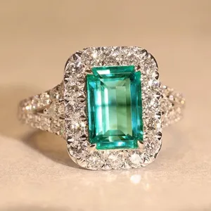 Anello vintage con gemma verde taglio smeraldo e zirconi bianchi scintillanti sul gambo.