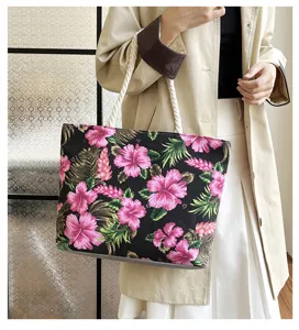 Detail view of large canvas tote bag with tropical pink floral print and white rope handles.