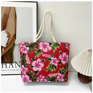 Detail view of the red floral canvas tote bag with tropical hibiscus print and white rope handles.