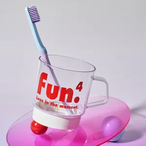 Transparent plastic toothbrush cup with toothbrush and creative red letter print for bathroom.